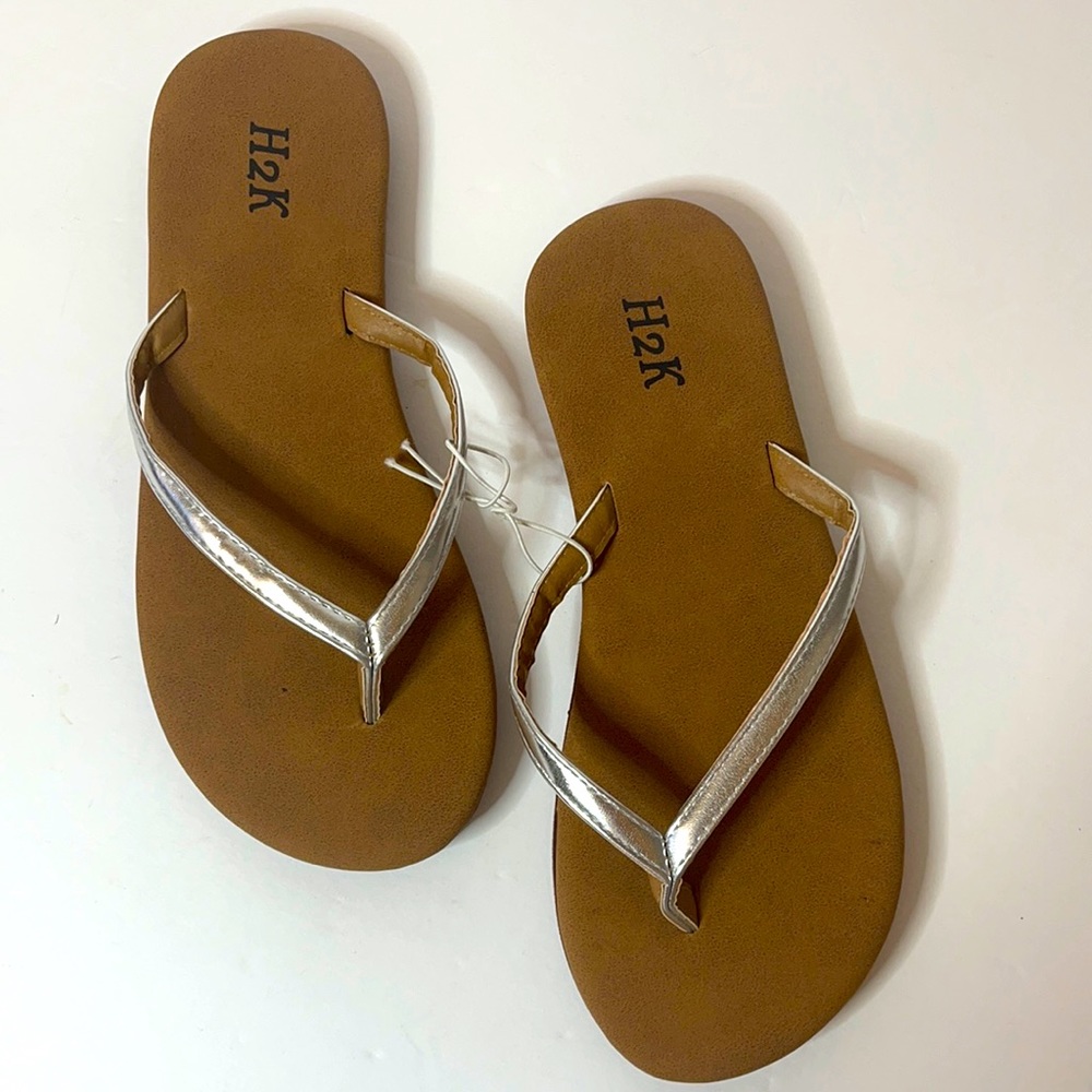Woman’s silver and tan summer flip-flops.